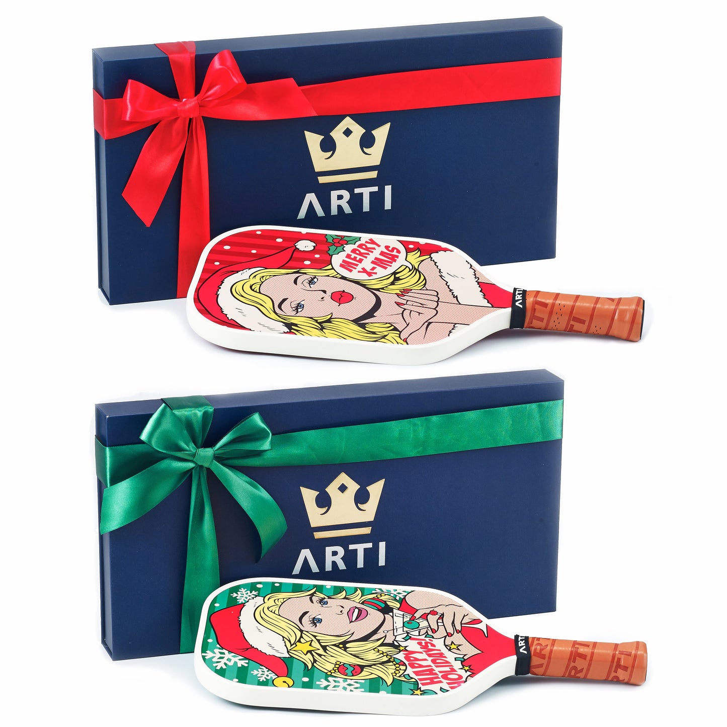 Two navy blue ARTI gift boxes with gold crown logos and “ARTI,” one with a red ribbon, the other green, each holds a USAPA approved ARTI Carbon Fiber Kristen&Kristy "X-MAS" Paddle featuring festive pop art women in T700 carbon fiber.