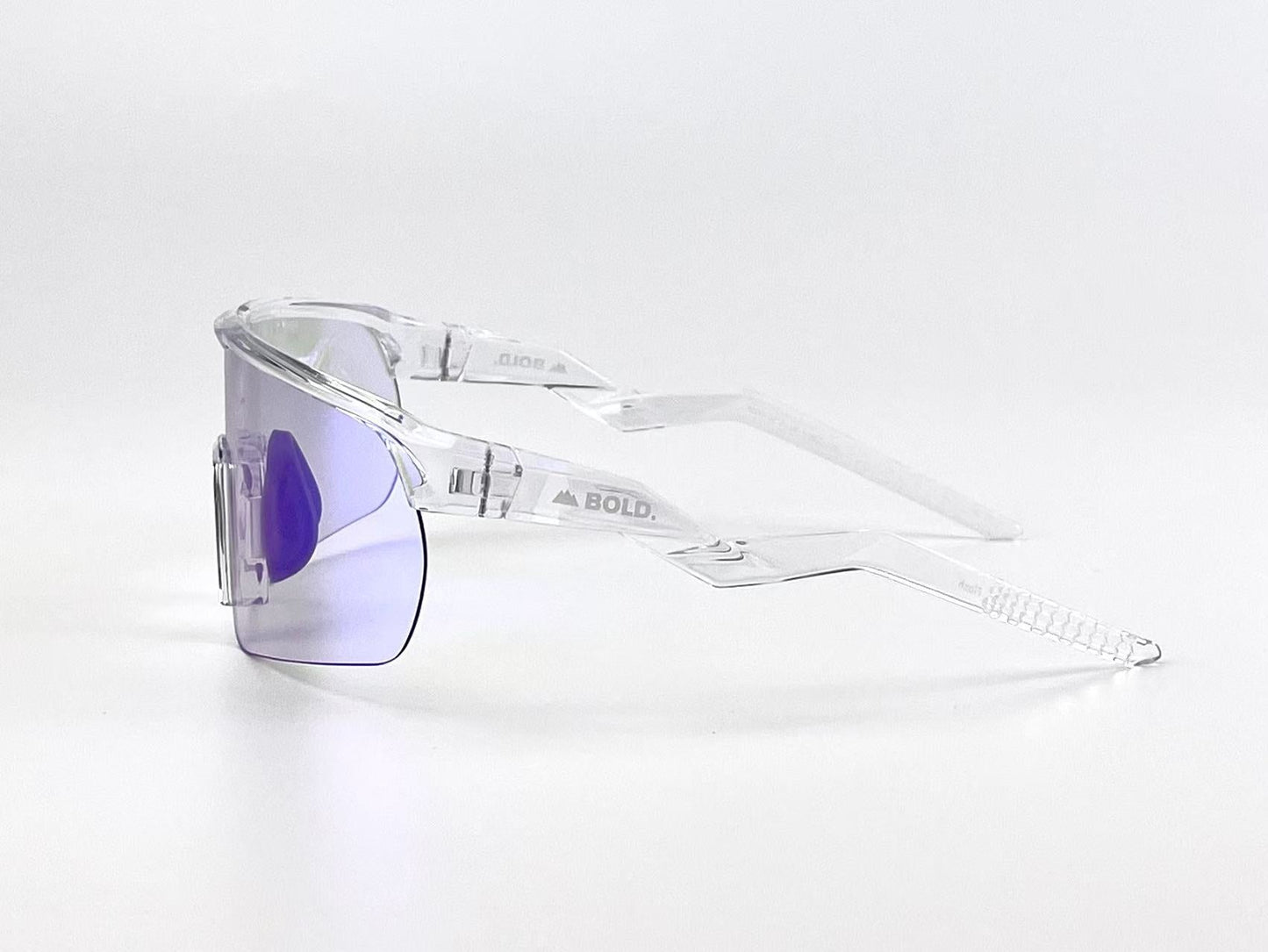 The BOLD Flash Photochromic Sunglasses by boldouterwear feature a clear, angular frame and a single purple-tinted visor lens. "BOLD." is visible on the left temple. Shown on a plain white background. Suitable for MTB, ski & lifestyle wear.