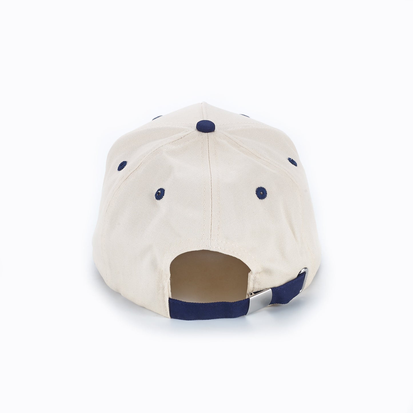 The ARTI Throwback Classic Rope Hat by ARTI is beige, shown from the back with a navy blue top button, navy eyelets, and an adjustable strap with metal clasp above the opening. Displayed on a plain white background.