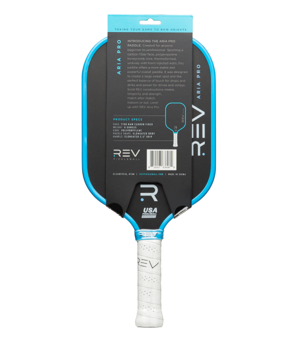 A blue and black REV Pickleball ARIA PRO paddle stands vertically with its back side forward. The white handle features a textured grip, and product specs plus branding appear on the carbon fiber face.