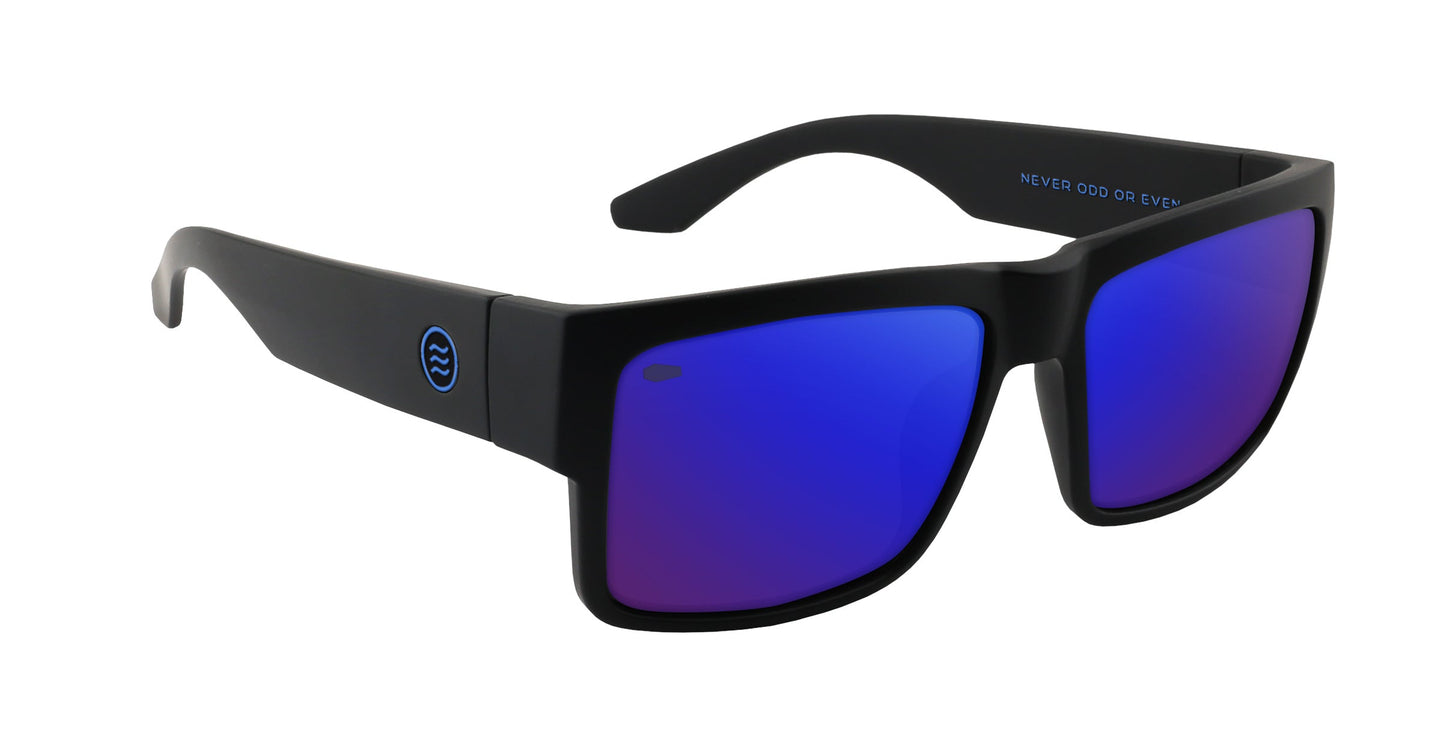 The Scythe by Neven Eyewear features matte black frames, wide arms, and reflective blue-purple lenses. A circular wave logo accents the left arm near the hinge, with “NEVER ODD OR EVEN” printed inside the right arm.