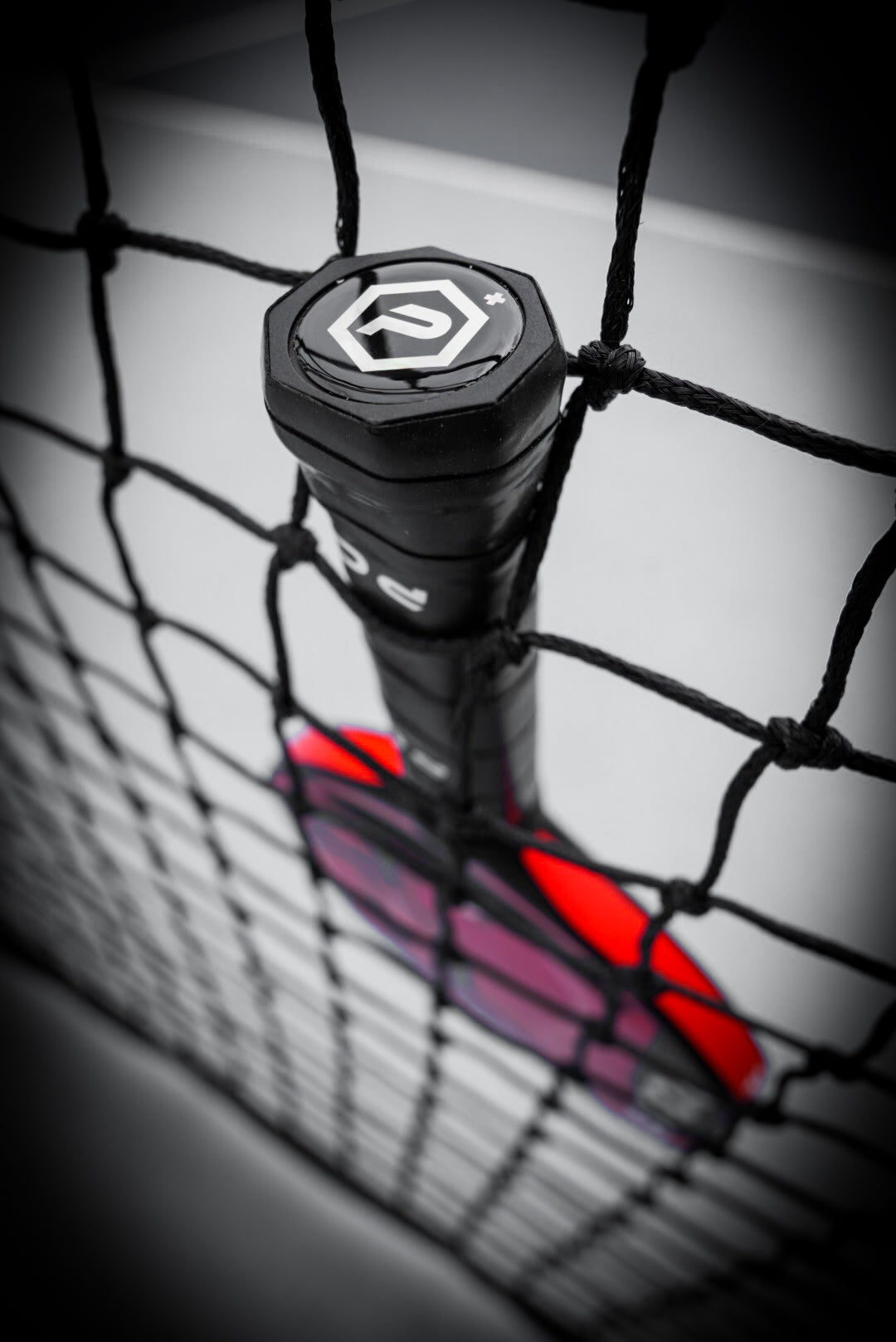 A tennis racket in a net highlights design innovation similar to the Potenza Pickleball ROSSO+ COREx3 professional paddle technology.