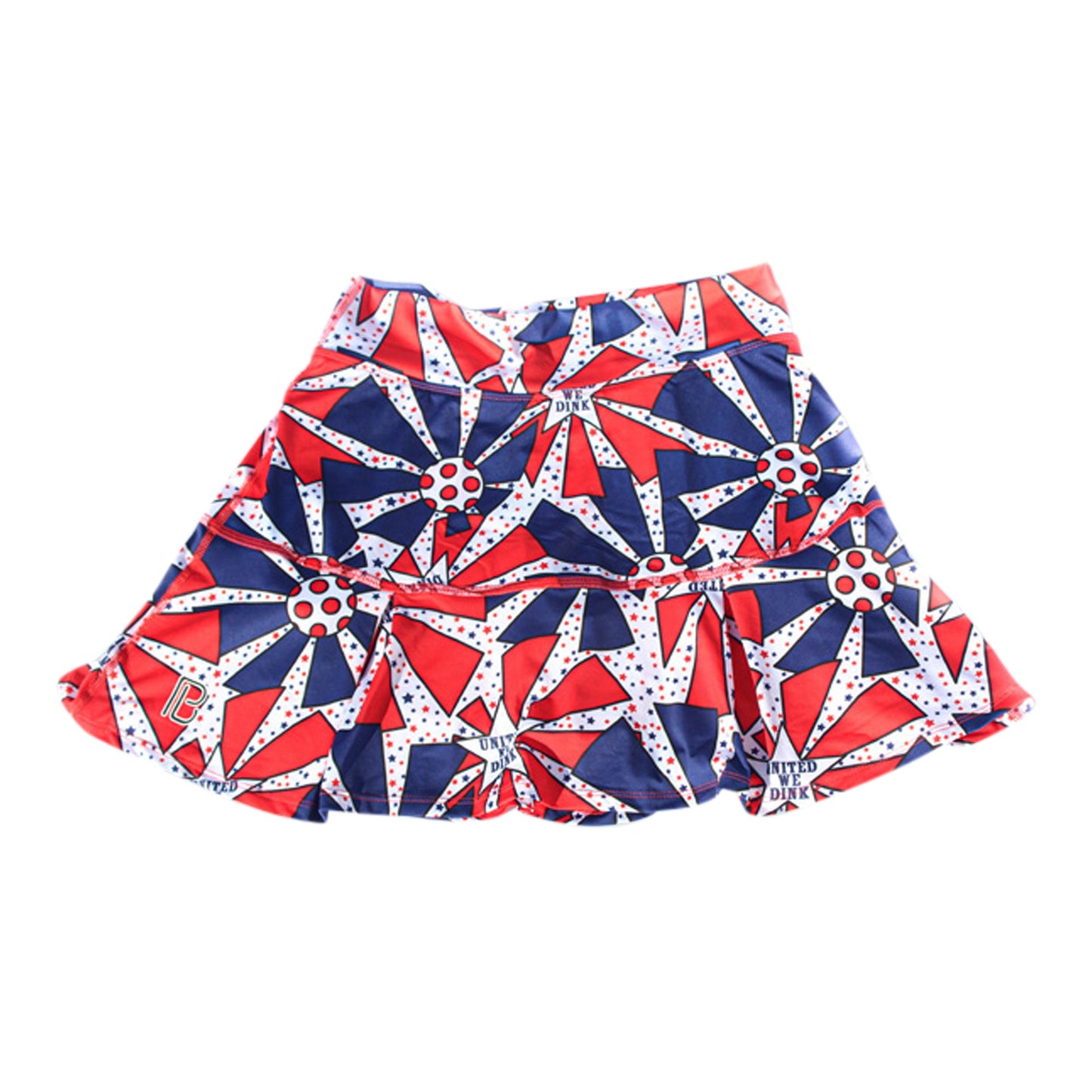 The Pickleball Bella PB Drop Pleat Skort United We Dink features a bold red, blue, and white geometric pattern with starbursts and polka dots—perfect for adding patriotic flair to your pickleball game.