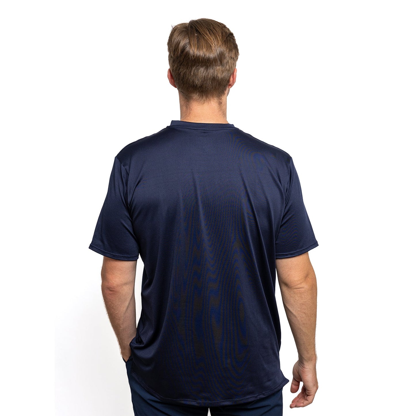 A man with short light brown hair faces away, wearing Diadem Sports - Men's Essential Everyday Tops by Diadem Sports. The dark navy athletic fit tee and pants highlight his upper body, designed for performance comfort against a white background.