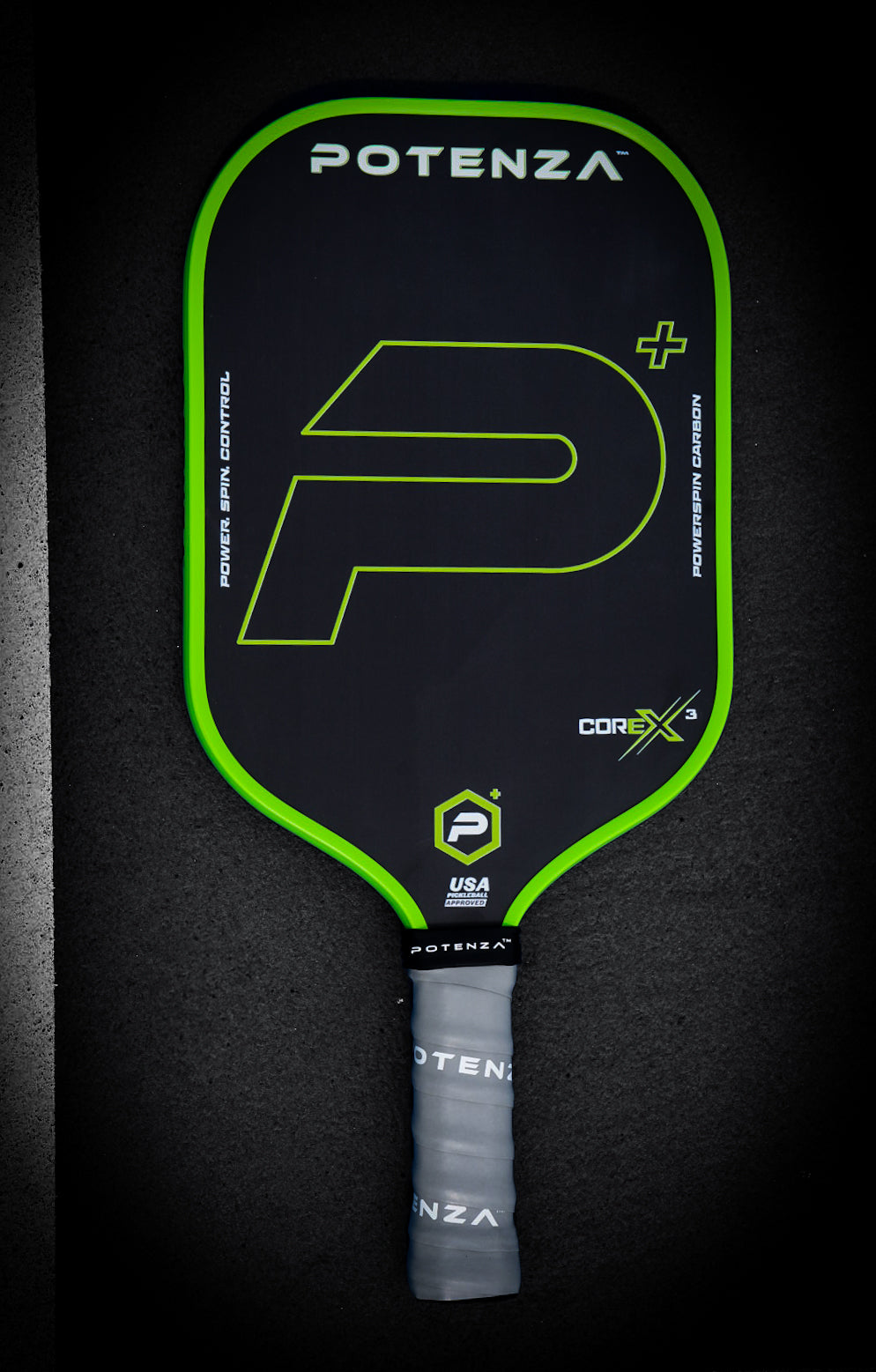 The Potenza Pickleball P+ PowerSpin Carbon COREx3 (Neon Green, Elongated Face) features a black design with neon green edge, large stylized P logo, gray grip, USA Pickleball logo near the bottom, and POTENZA branding at the top.