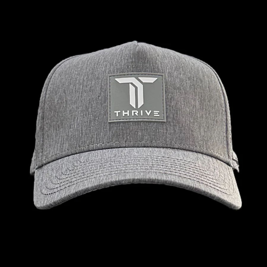 The Thrive Elite Tour Hat by Thrive Pickleball is a light gray baseball cap with a curved brim, featuring a square black patch on the front with a stylized white T logo above the word THRIVE.