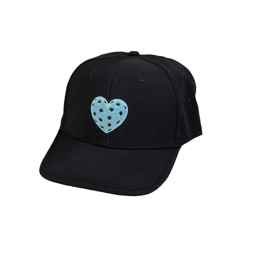 The SEXY Brand I ❤️ Pickleball AquaSnapBack in Black features a curved brim, ventilation holes, and a light blue heart with black polka dots embroidered on the front. Displayed against a white background.