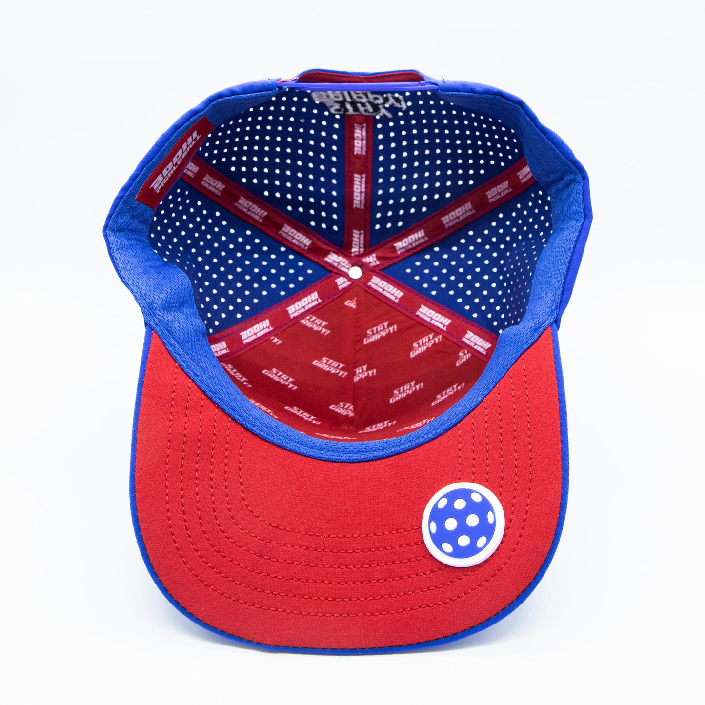 The ICON Snapback by Bodhi Performance is shown from underneath, with a red brim, blue and white polka dot sticker, blue crown, red and white STARTER headband, navy lining with white polka dots, and sweatband.