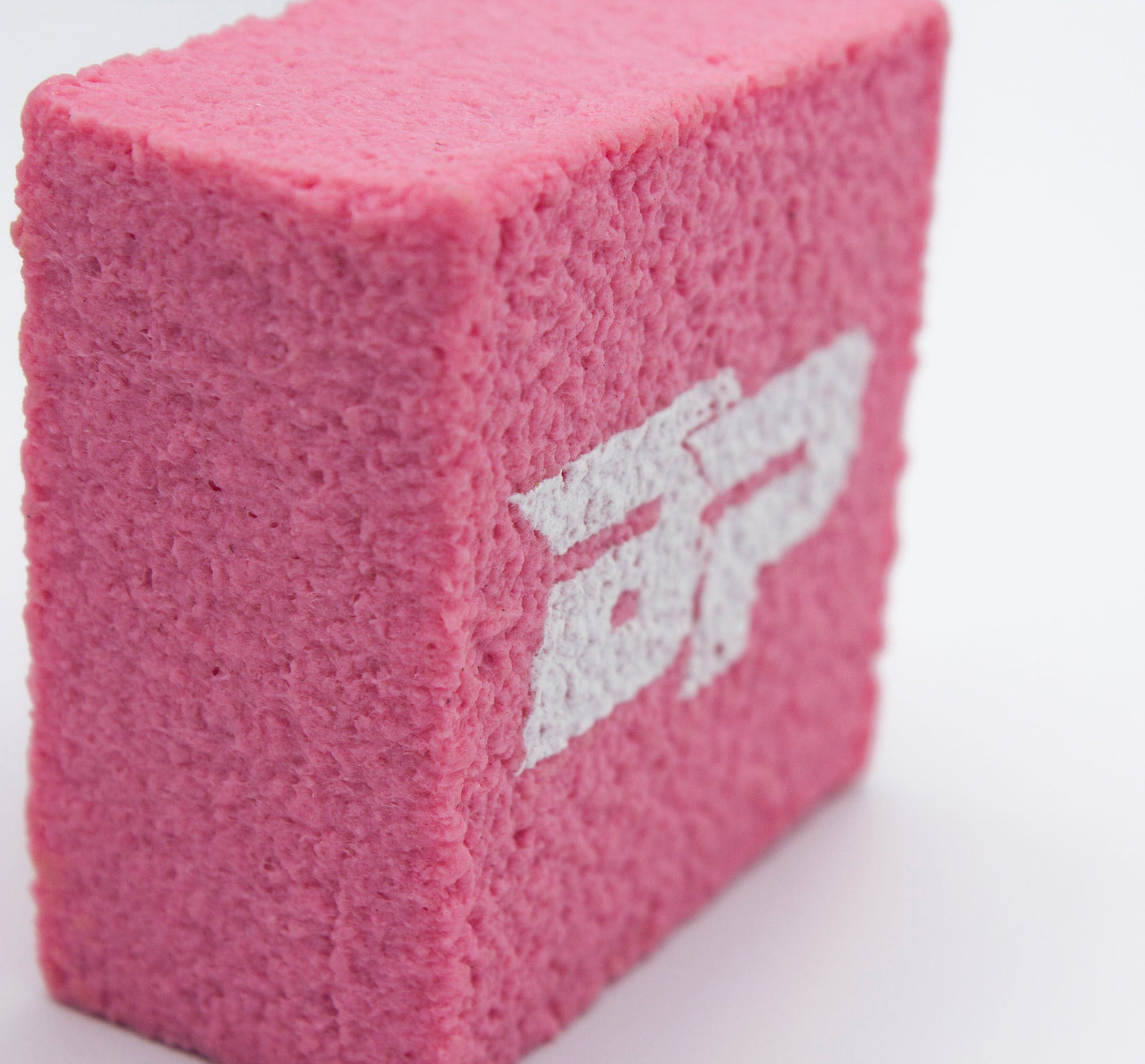 A rectangular pink PROeraser™ paddle cleaner by Bodhi Performance stands upright on a white surface. The bold white "AP" letters face the camera, while soft lighting highlights its rough texture and crisp edges.