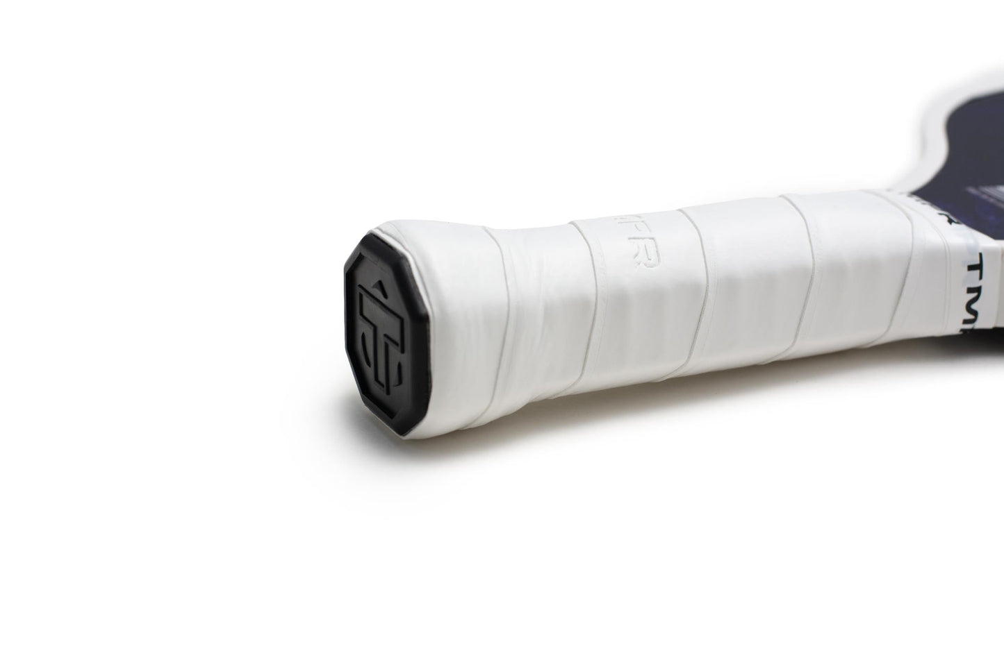 Close-up of the TMPR Sports Expanse LX | Indigo Ice paddle handle wrapped in white overgrip tape. A black, stylized logo decorates the end cap. Only part of the wide-body handle appears against a plain white background.
