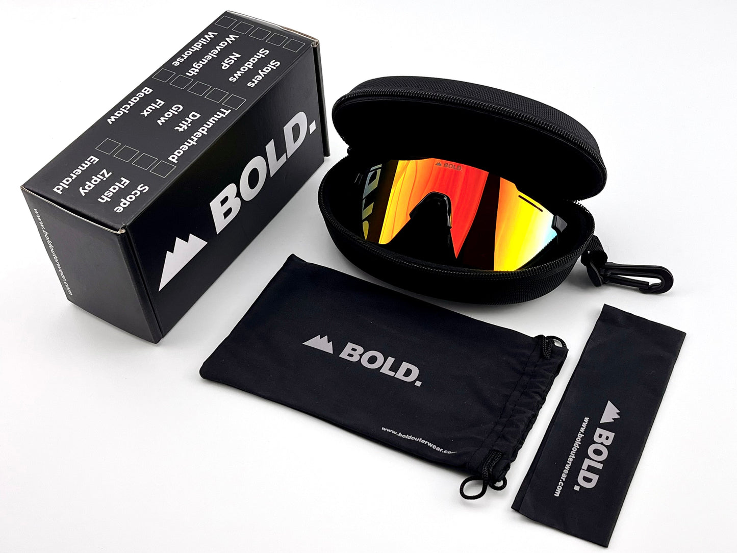 A black boldouterwear box, soft pouch, and lens cloth are arranged next to a zippered hard case holding red-yellow mirrored BOLD Scope Performance Sunglasses—MTB, ski & lifestyle eyewear—showcased on a white surface for a sleek, sporty look.