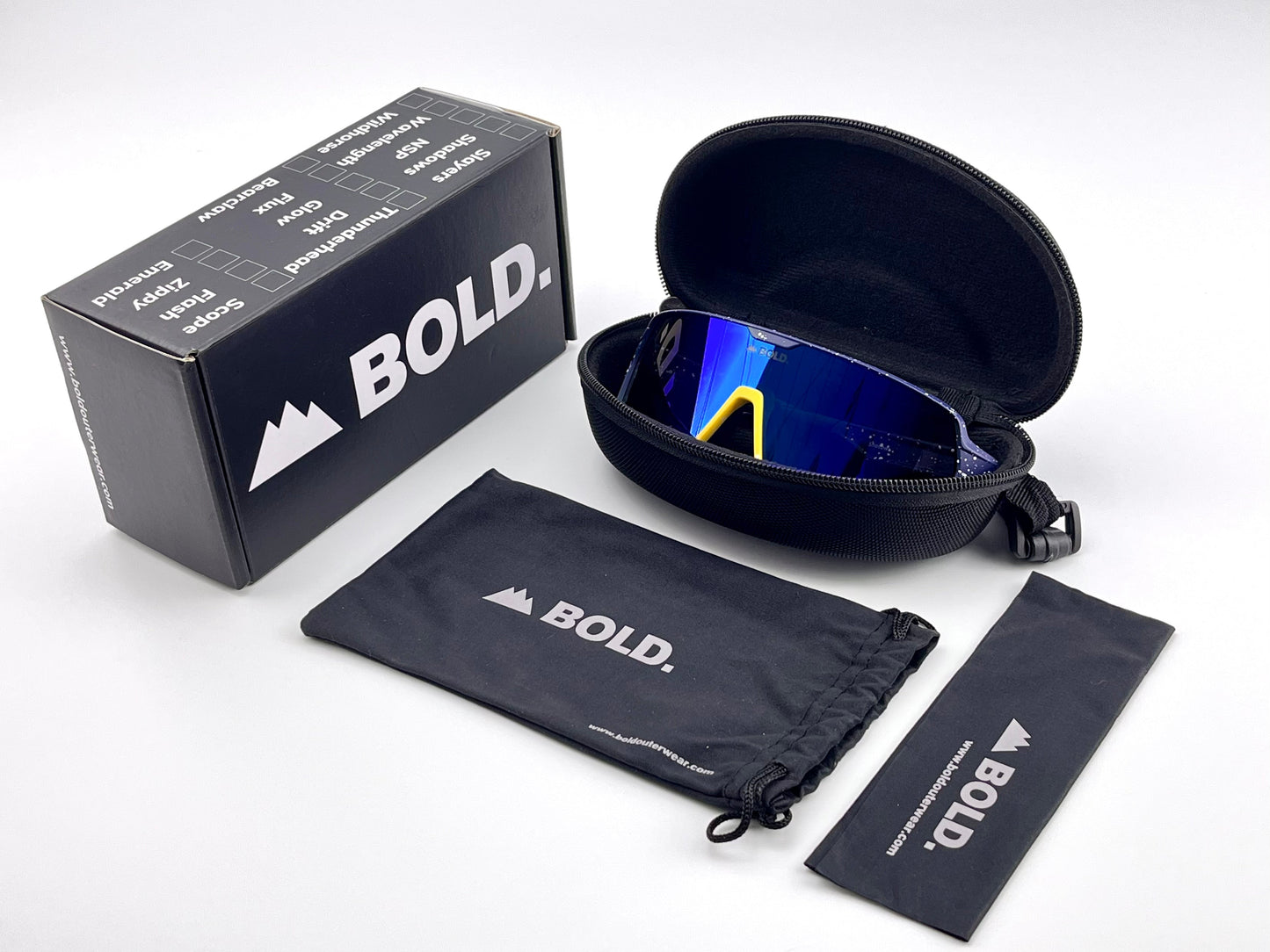 The BOLD Shadows Performance Sunglasses by boldouterwear feature blue lenses, a wraparound design, and yellow arms. Shown in an open black zippered case with a branded box, drawstring pouch, and cleaning cloth on a white background.
