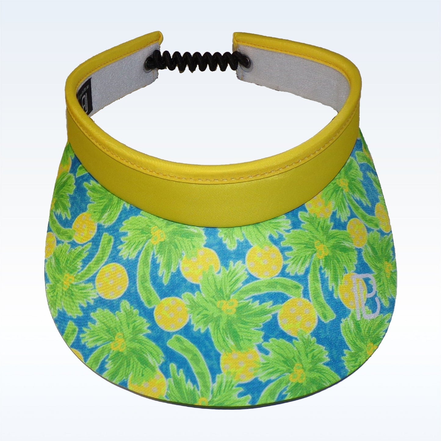 The Pickleball Bella PB Visor Palms 1 is a lightweight, quick-dry visor with a wide curved brim. It features green palms and yellow pineapples on blue, plus a solid yellow band and black elastic strap for comfort and style.