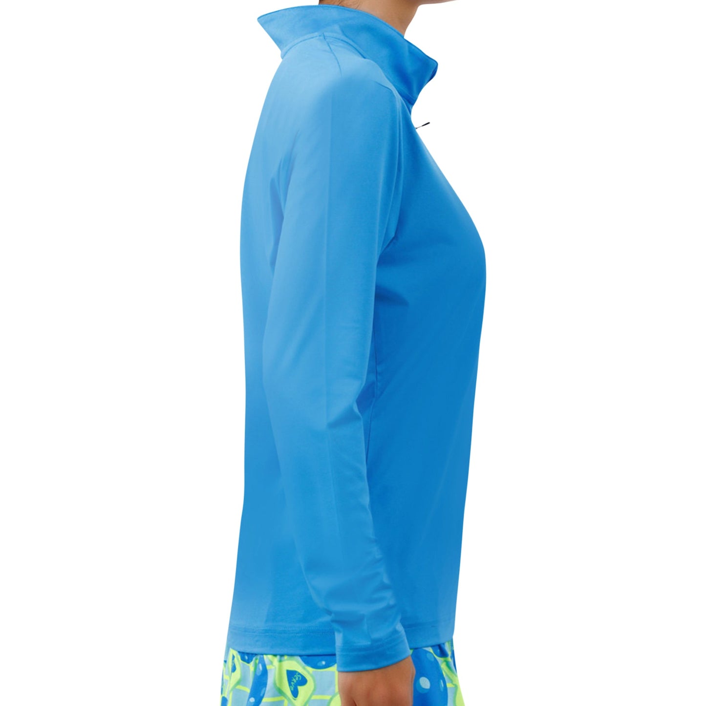 A person in profile wears the Pickleball Bella PB 1/4 Zip Long Sleeve Electric Blue pullover, paired with colorful patterned shorts. The plain white background highlights their SPF 50+ UV protection outfit.