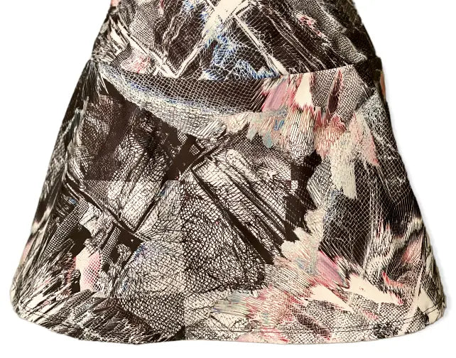 The Nola Modern Mesh Print Court Skirt by Runway Athletics features a flared A-line silhouette with bold black, white, light pink, and pale blue abstract brushstrokes and a visible top seam. Smooth fabric includes a moisture-wicking under-short for comfort.