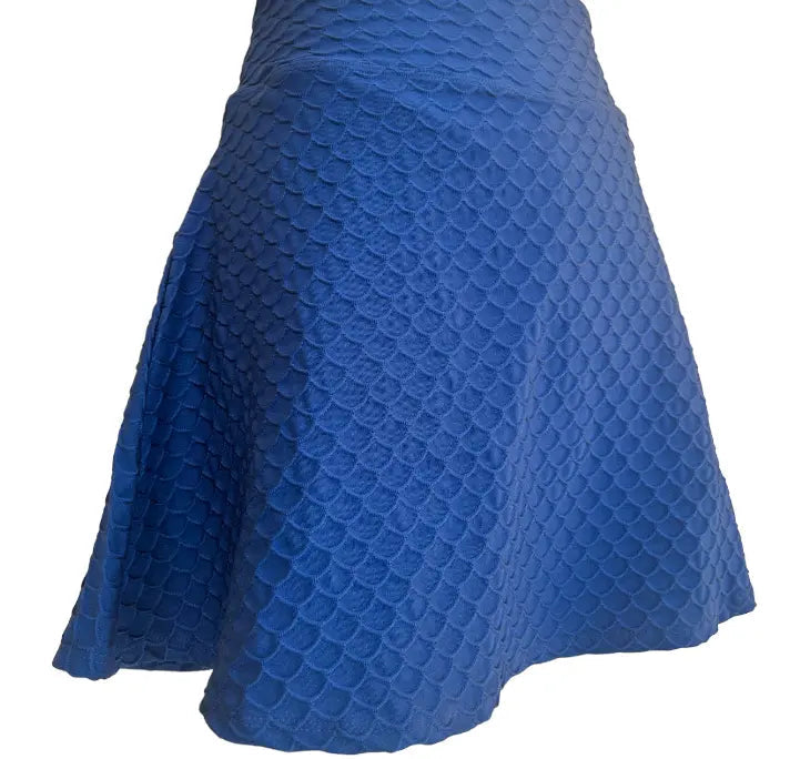 The Runway Athletics 16.5" Nola Scallop Skirt - Navy is a knee-length, A-line skirt with a mermaid scale textured pattern, slight sheen, and soft fabric. It features a hidden moisture-wicking undershort for comfort. Shown on a white background.