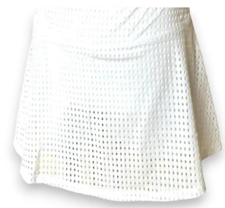 The Mesh Club Skirt - White by Runway Athletics features a flared A-line silhouette, grid-like cutouts in lightweight fabric, a fitted waistband, and a semi-sheer finish for striking texture and style.