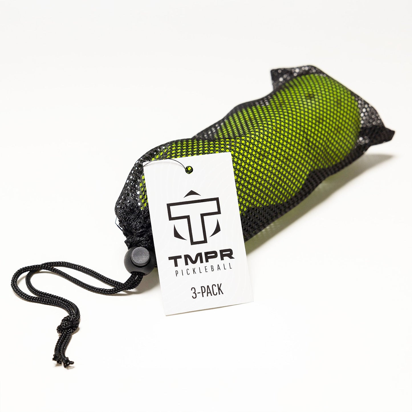 A black mesh drawstring bag holds six yellow-green TMPR Sports T-40 outdoor pickleballs. A white tag with the black TMPR Pickleball logo and “6-PACK” hangs from the bag. The background is plain white.