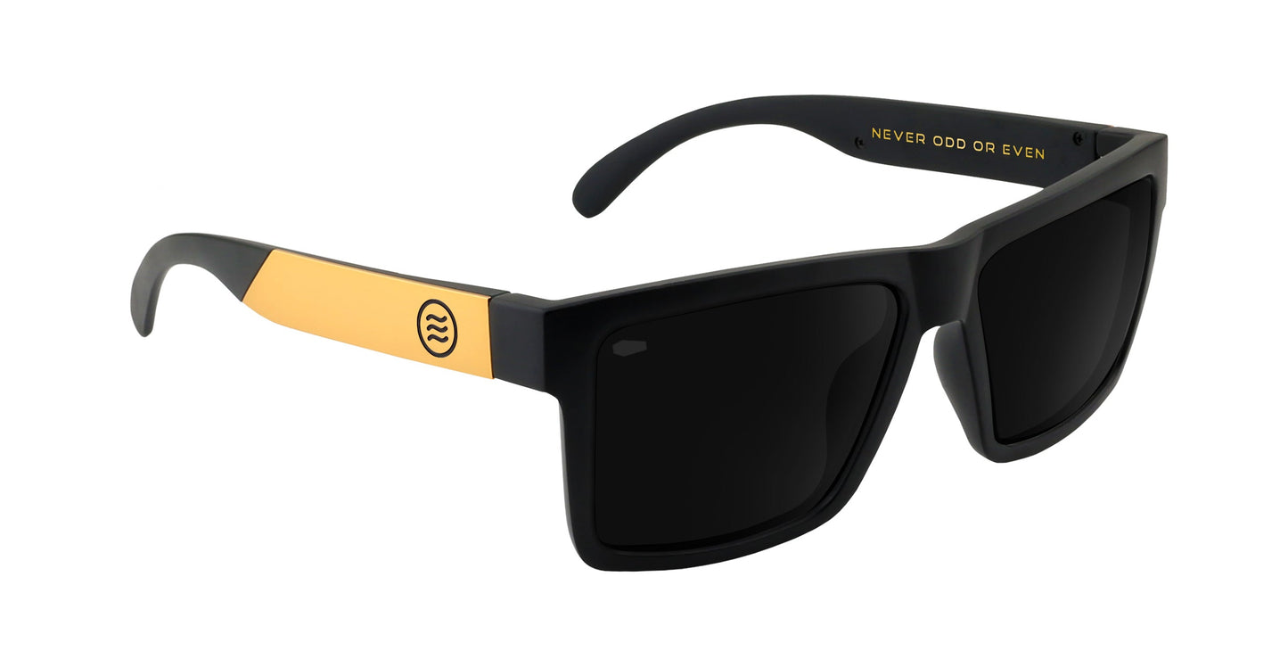The Prospector XL sunglasses from Neven Eyewear feature black rectangular frames with polarized black lenses, gold arm accents, and "NEVER ODD OR EVEN" in gold plus a circular logo on the arms.