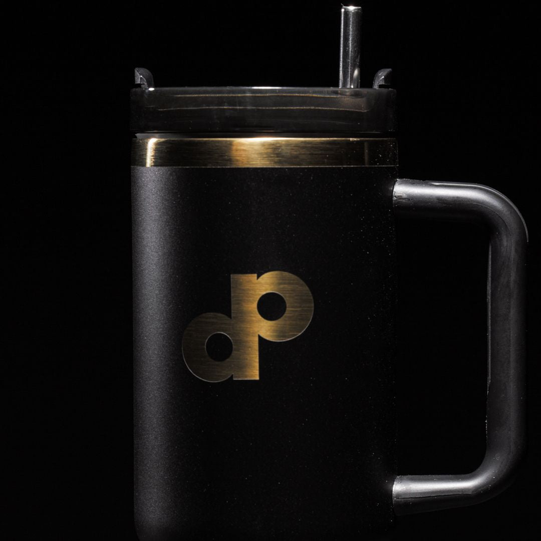 The Dope Pickleball Co. High Roller 40 oz. Tumbler features matte black, a gold and black "dp" logo, large handle, metallic gold band, transparent lid, and reusable straw—all shown against a black background.