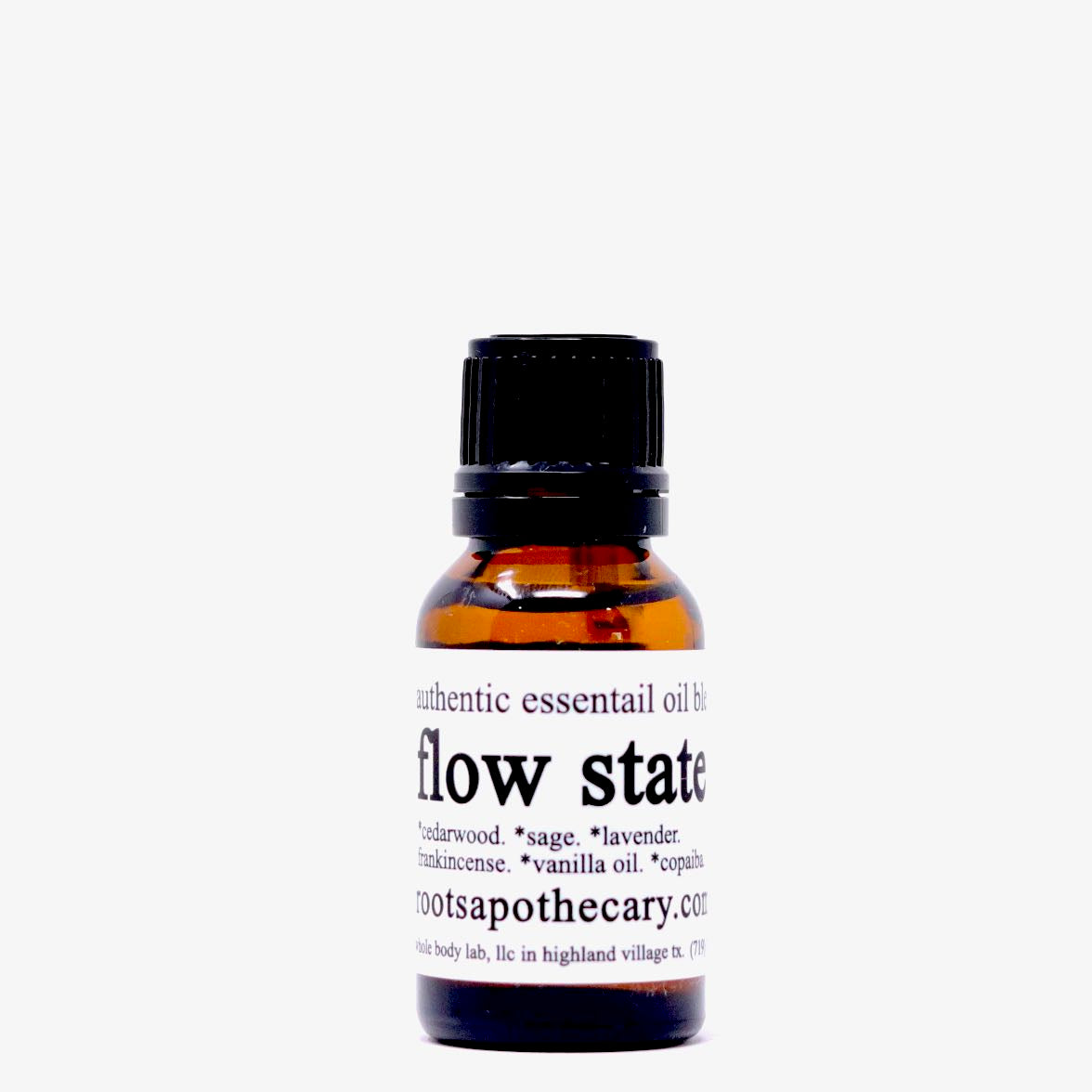 A small amber glass bottle with a black cap labeled “flow state essential oil blend” from Roots Apothecary lists sandalwood, sage, lavender, frankincense, vanilla, and copaiba oils in black text on a white label.