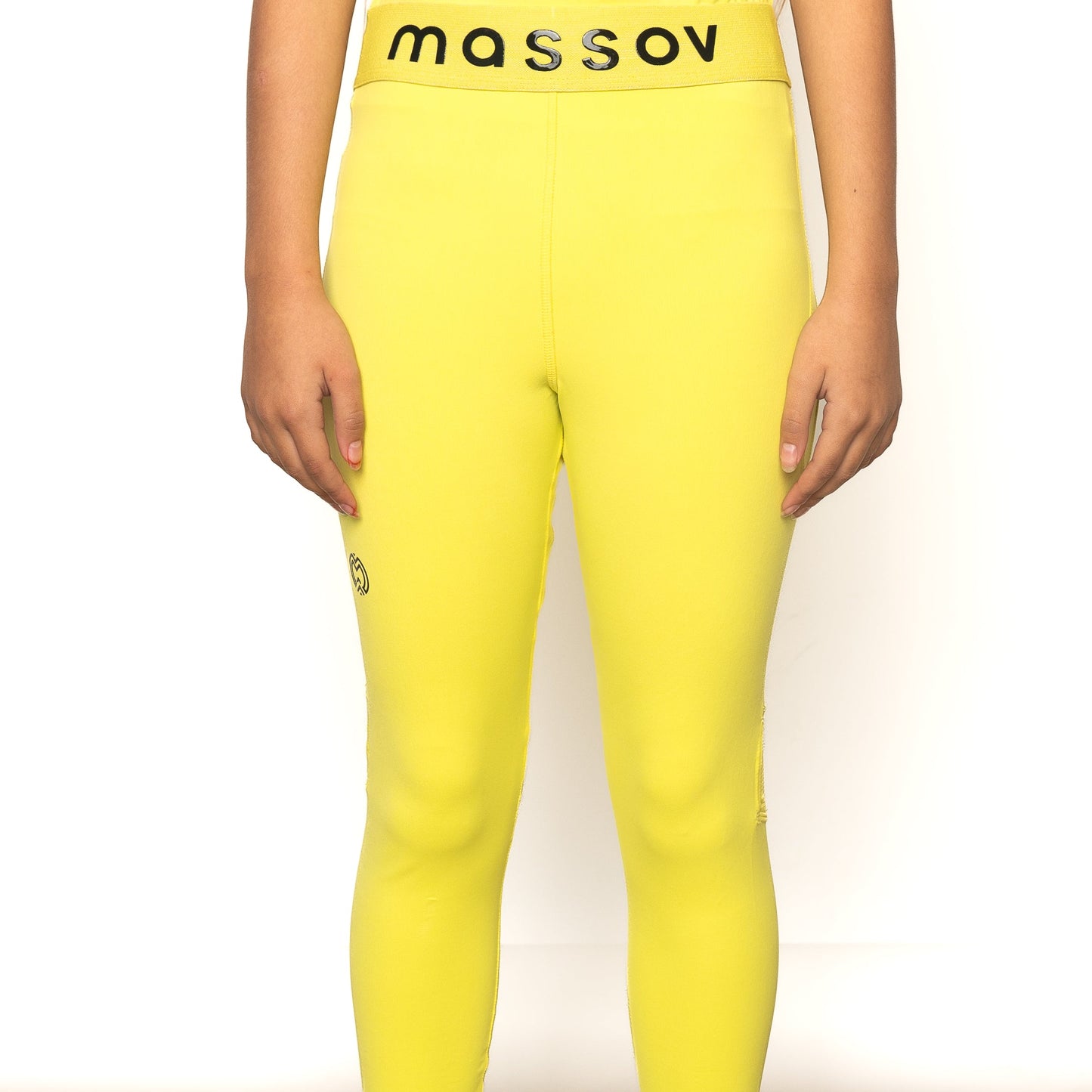 Shown from waist to feet, a person stands against a white background, wearing bright yellow ProForm® Girls' Athletic Leggings by Massov. The mid-rise leggings have a black "massov" waistband, and the person's hands rest at their sides.