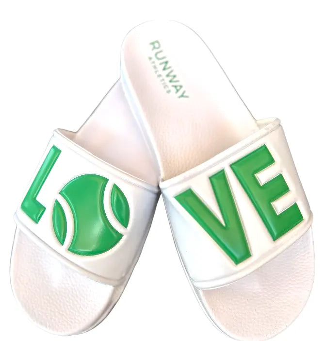 The Tennis LOVE After Play Tennis Slides by Runway Athletics feature white slides with green lettering—one displays "L O" with a tennis ball as the "O", the other "V E". Labeled RUNWAY on the insole, they're a fun personalized gift for tennis fans.
