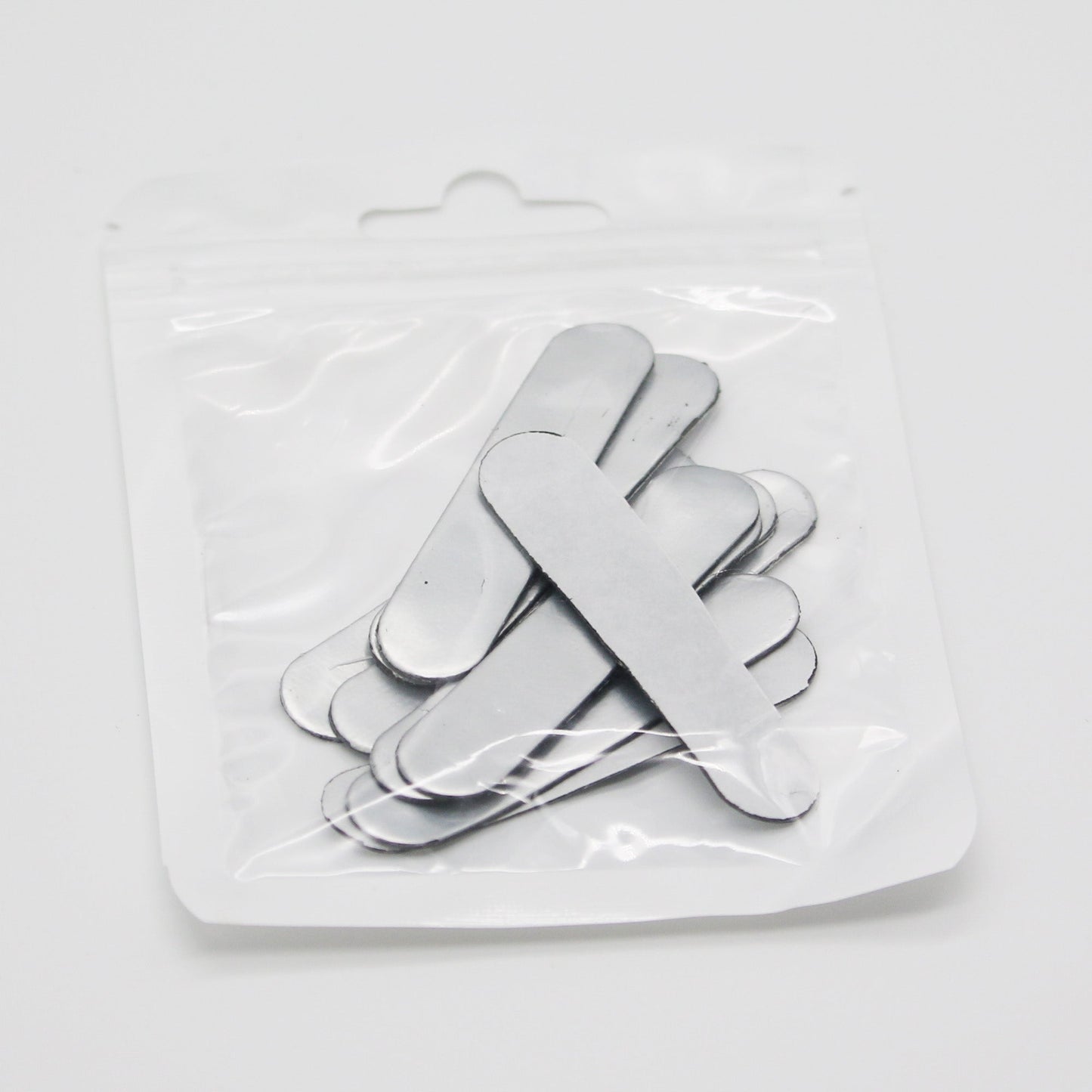 The 4Joy Paddle Weights by 4Joy Paddles are flat, silver metal strips with rounded ends, neatly stacked in a clear resealable plastic bag—perfect for adding balanced weight to your pickleball paddle.