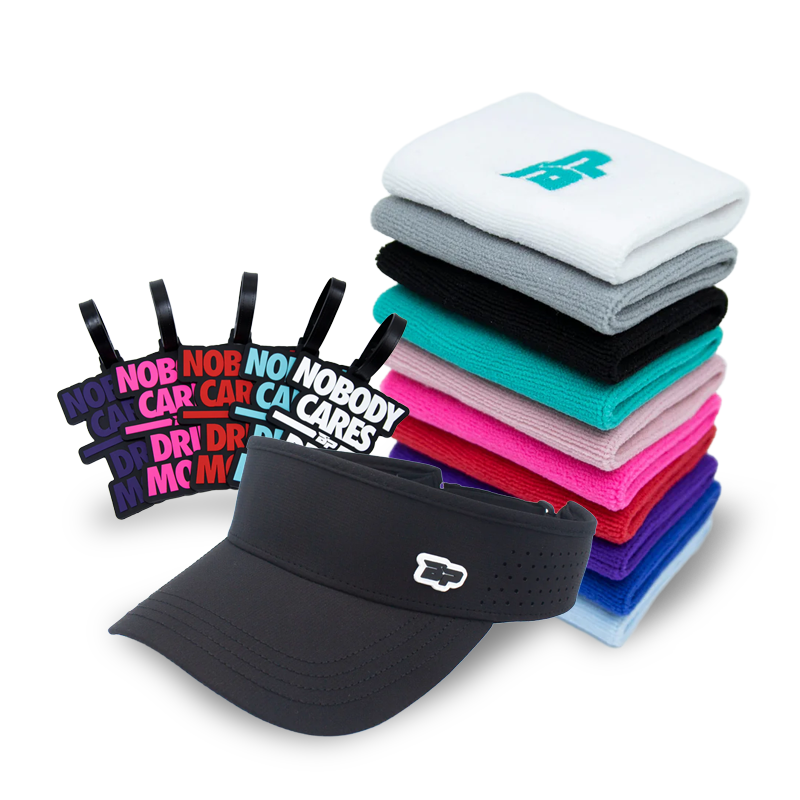 A stack of folded headbands in various colors, four black keychains reading “NOBODY CARES,” and a black visor with a small white logo are arranged on a white background.