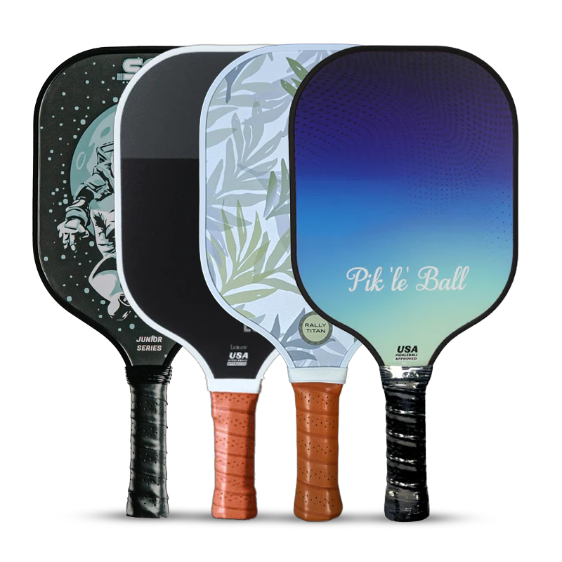 Four pickleball paddles stand upright in a row, each with a unique design and brown or black grip. Designs include an astronaut, leaves, a sleek black panel, and a blue gradient with Pik ‘le’ Ball text.