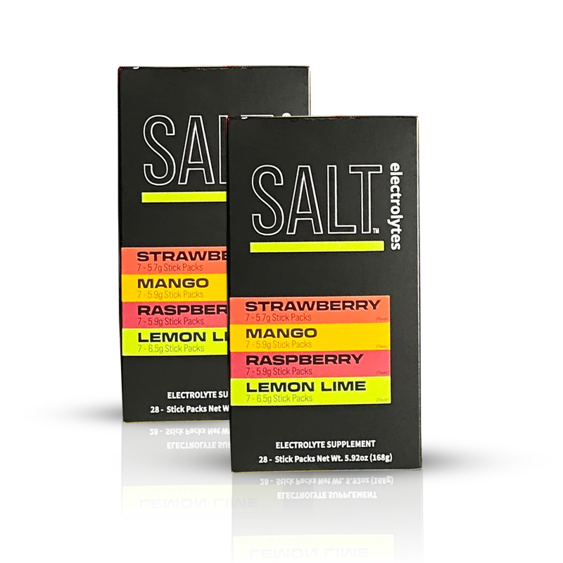 Two black SALT. electrolytes boxes stand with front labels showing flavors: Strawberry, Mango, Raspberry, and Lemon Lime. The text highlights “electrolyte supplement” and 28 stick packs per box.