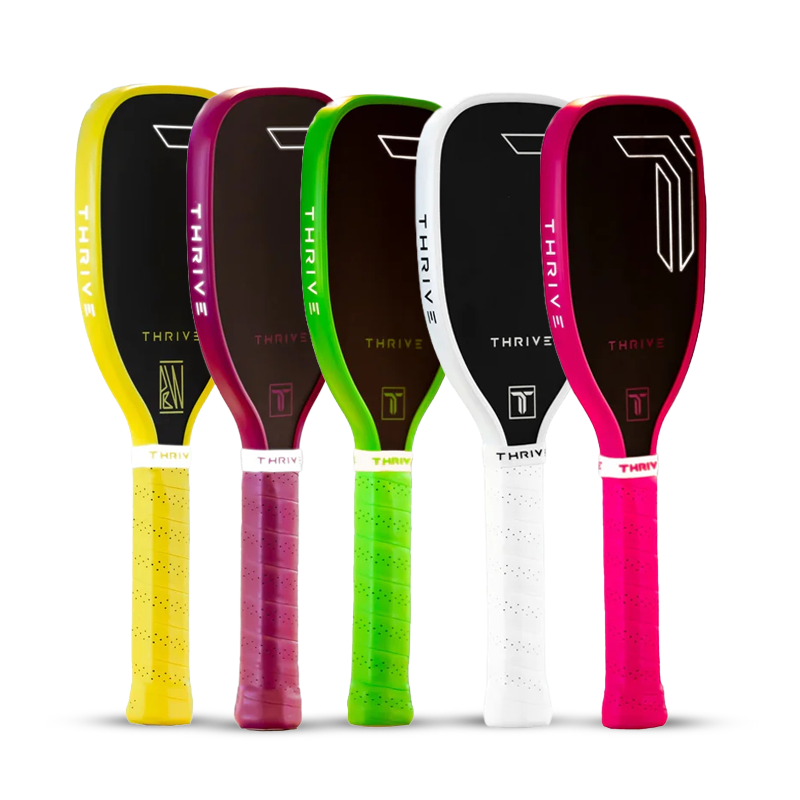 Five pickleball paddles stand upright in a row, each with a black face and colored edge and grip: yellow, purple, green, white, and pink. All paddles have Thrive branding.