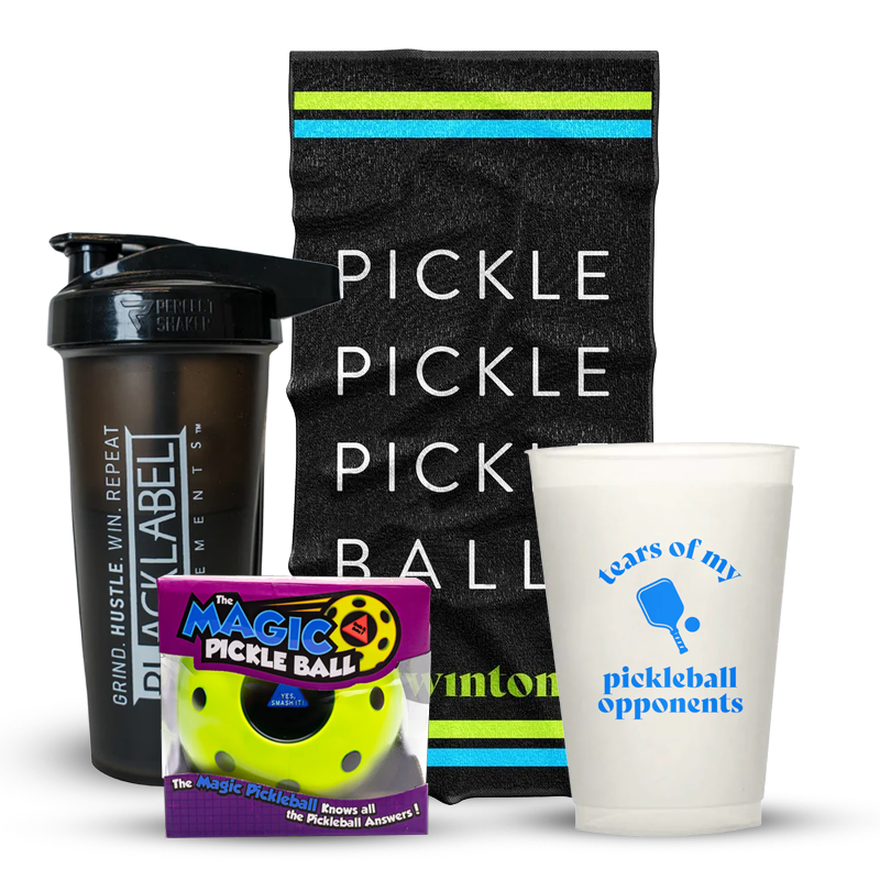 A black shaker bottle, a striped black towel with PICKLE PICKLE BALL in white, a plastic cup with tears of my pickleball opponents in blue, and a package labeled The Magic Pickle Ball.