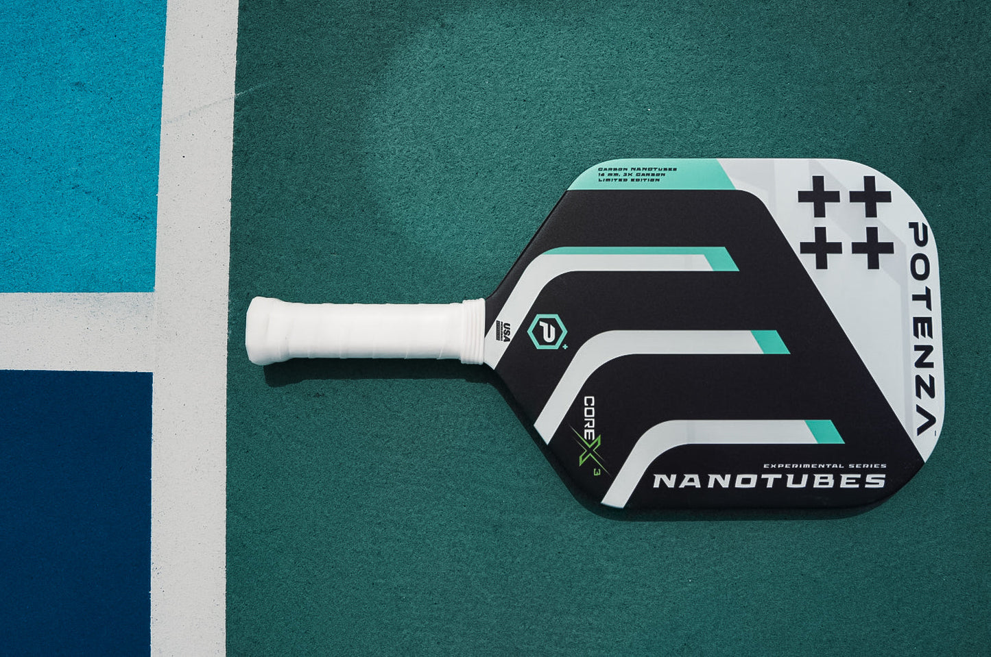 The Potenza Pickleball Carbon Nanotubes+ COREx3 paddle, with black, white, green, and gray geometric designs and a white grip, showcases advanced carbon nanotube construction on a teal court.