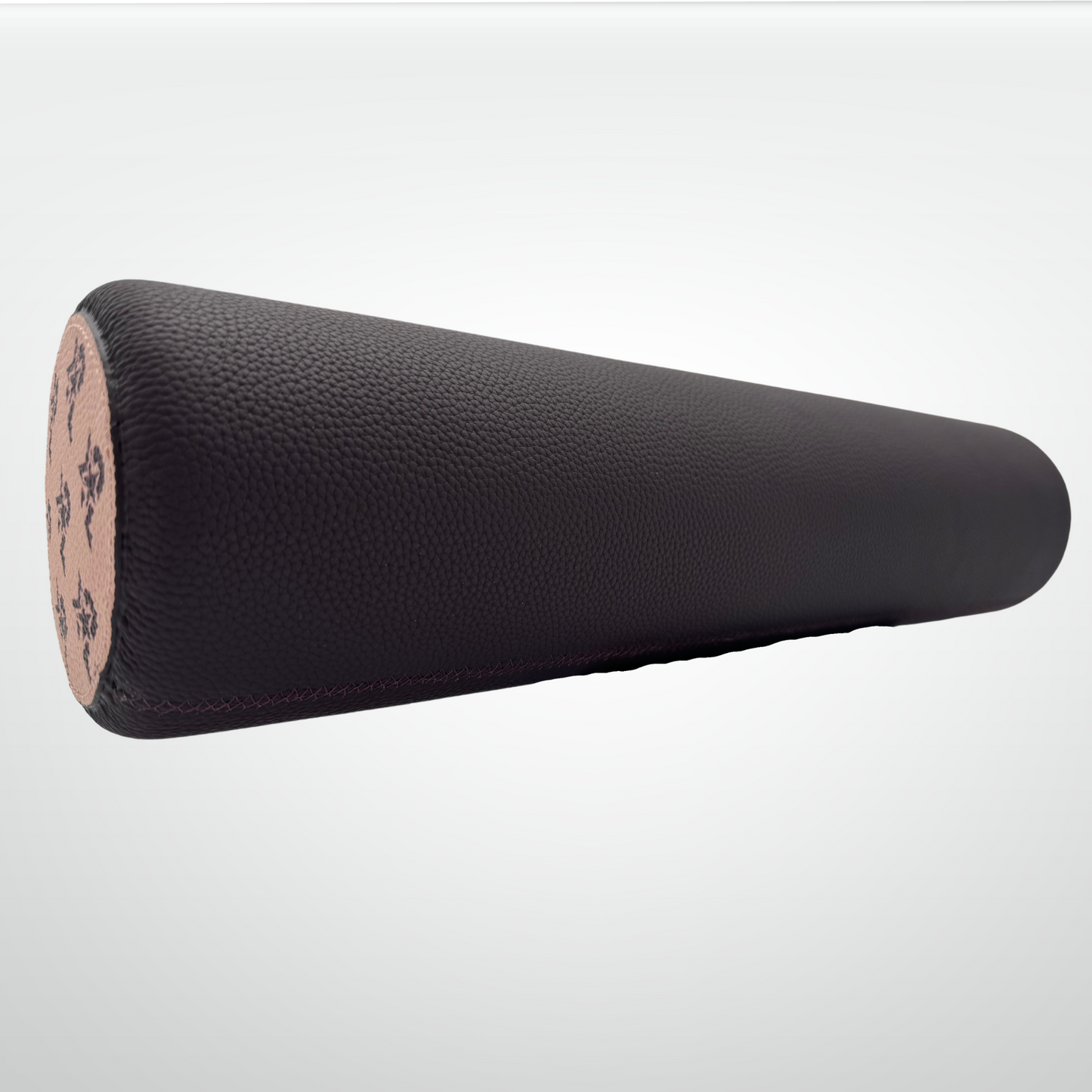A close-up of the iReliev I AM Leather-Wrapped Cork Stretching and Massage Roller shows its black, textured cylindrical body with a natural cork end adorned by subtle dark floral designs, all set against a light gradient gray background.