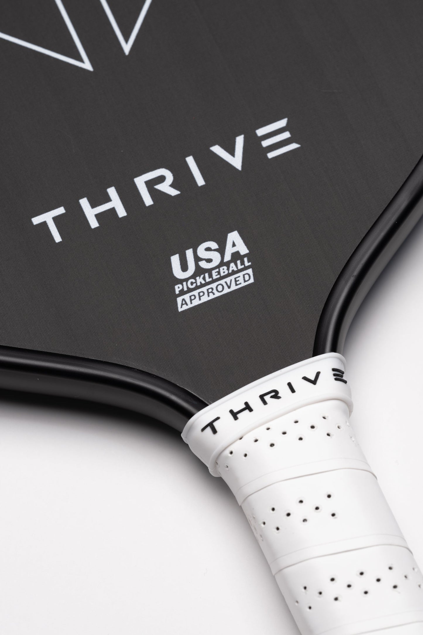 Close-up of the RUSH 13 paddle by Thrive Pickleball with THRIVE on its TORAY T700 carbon fiber face. USA Pickleball Approved, it has a white perforated grip and comes with a weight card, cover, paddle eraser, and lead weights.