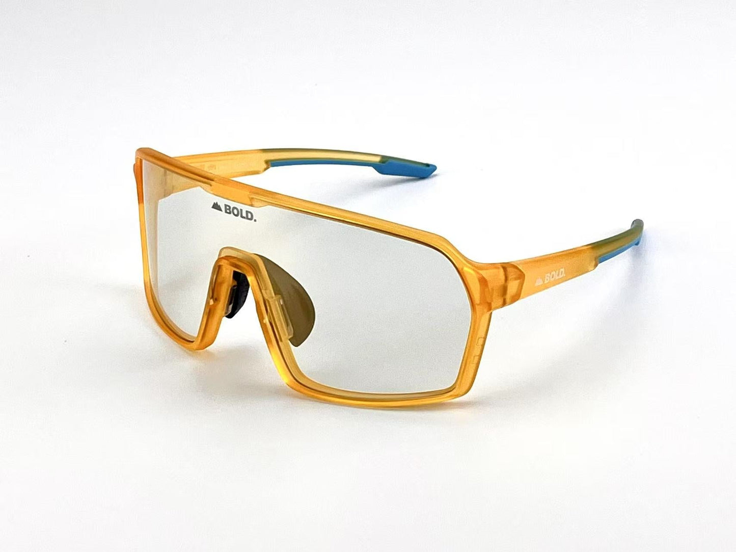 The BOLD Drift Photochromic Sunglasses by boldouterwear feature a single large reflective lens, thick translucent orange frame, and orange temples with blue tips. "BOLD." is printed in black on the top left lens and side of the frame.
