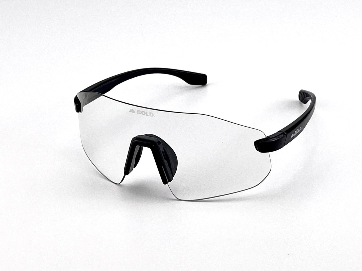 The BOLD Emerald Photochromic Sunglasses by boldouterwear feature a clear frameless design, single curved lens, black arms, adjustable nose pad, and “BOLD.” printed on the left lens. Shown against a plain white background.