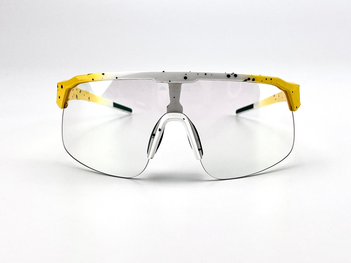 The BOLD Zippy Photochromic Sunglasses by boldouterwear are lightweight, sporty, and frameless with clear lenses. They feature a white top edge with black speckles, bright yellow accents, slim arms, and white nose pads—ideal for MTB, ski & lifestyle.