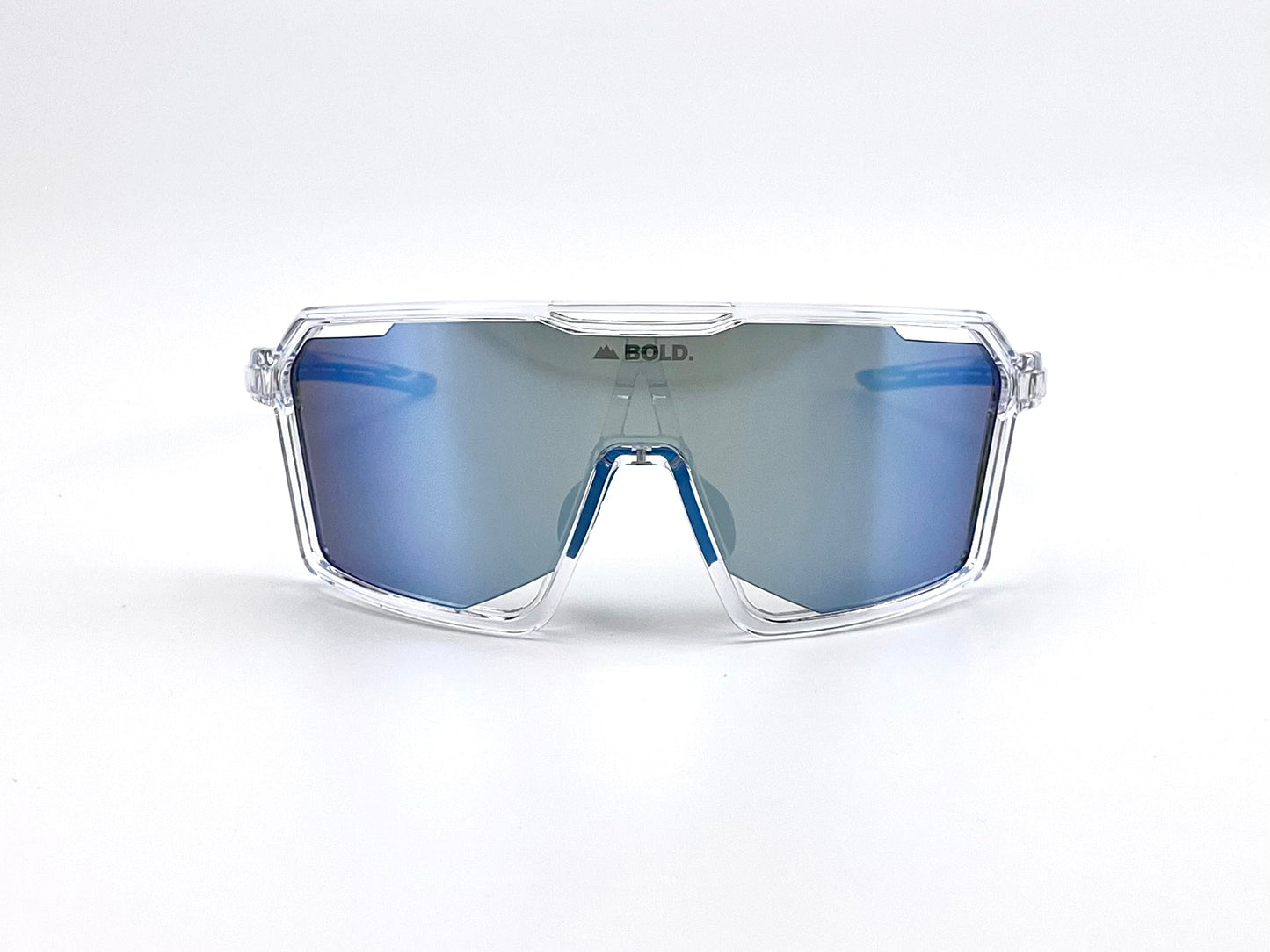 The BOLD Flux Performance Sunglasses by boldouterwear feature an oversized, sporty wraparound design with a clear frame and blue mirrored lenses. "BOLD." is printed on the top center. Provides UV protection; perfect for MTB, ski, and lifestyle wear. Background is plain white.