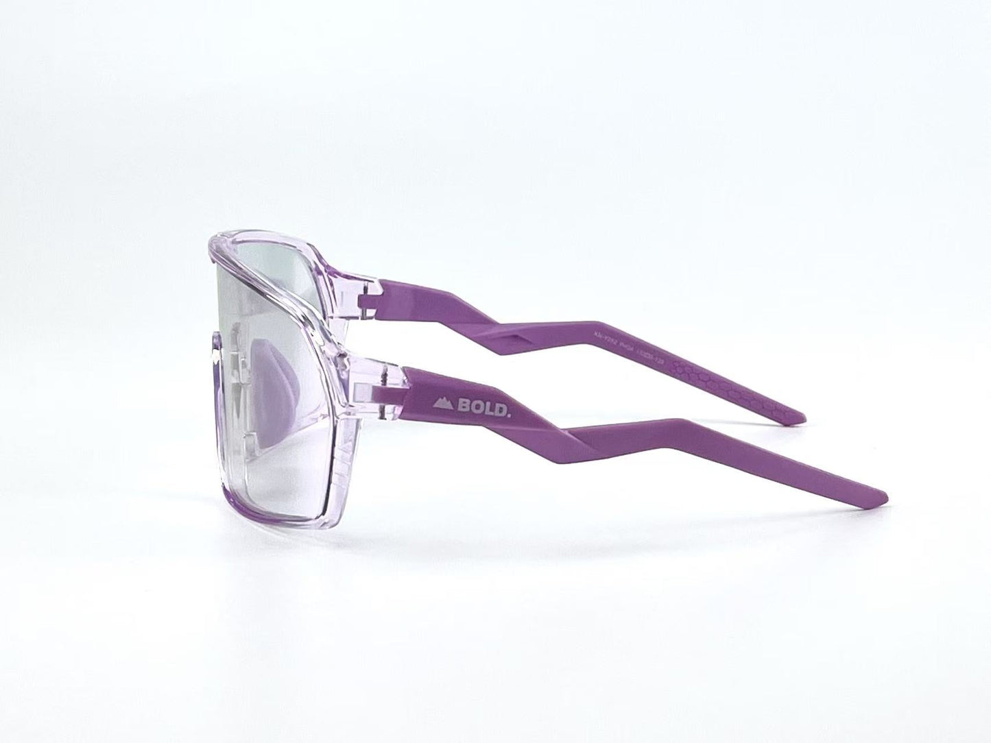 The BOLD Glow Photochromic Sunglasses by boldouterwear feature clear, square lenses and transparent purple frames. Solid purple zigzag temples display "BOLD." in white. Perfect for MTB, skiing, or lifestyle wear against a plain white backdrop.