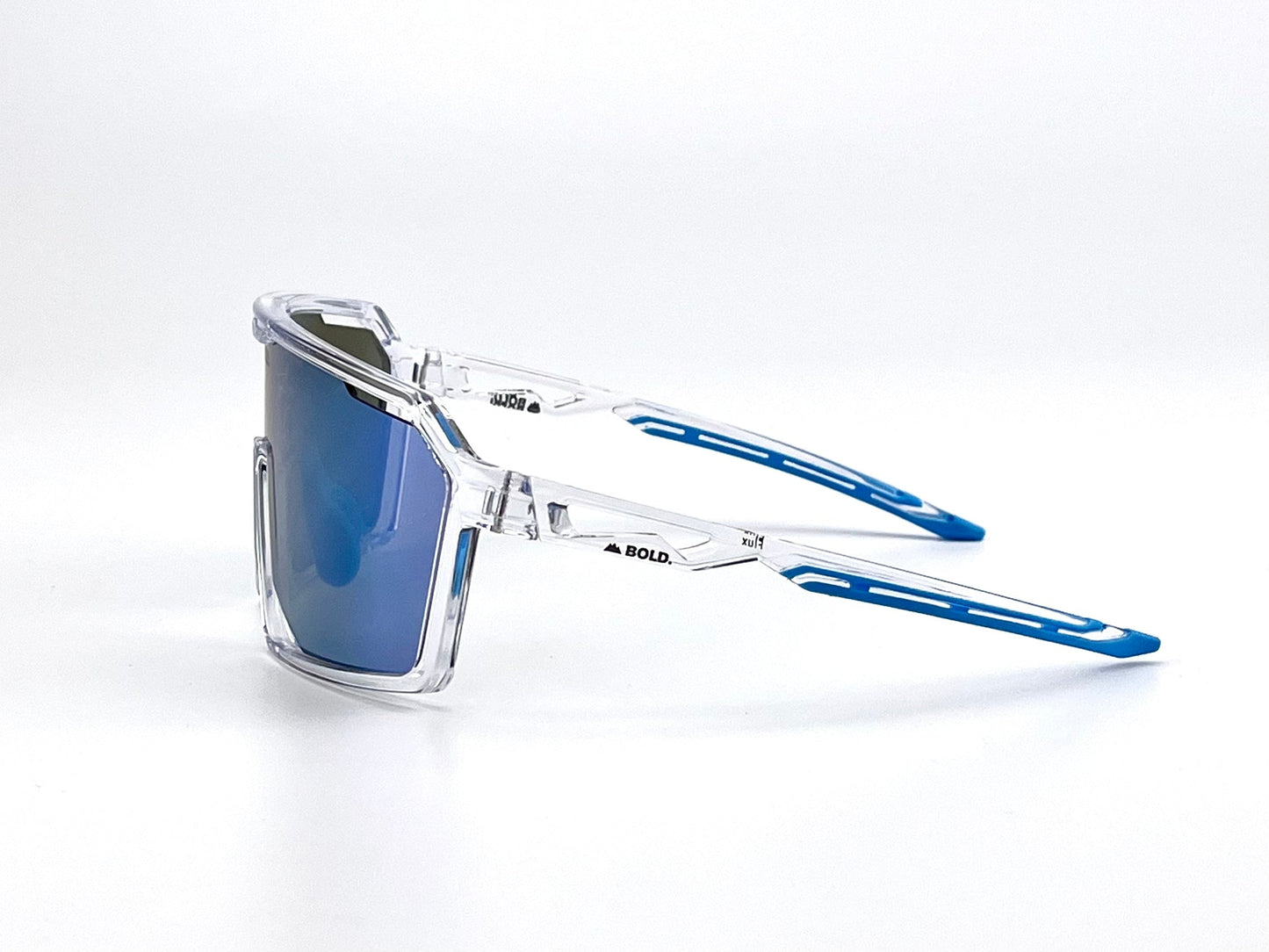 The BOLD Flux Performance Sunglasses by boldouterwear feature clear, angular frames with reflective blue lenses and matching temples. Designed for MTB, ski, and lifestyle use, they offer modern aerodynamics and full UV protection against a plain white background.