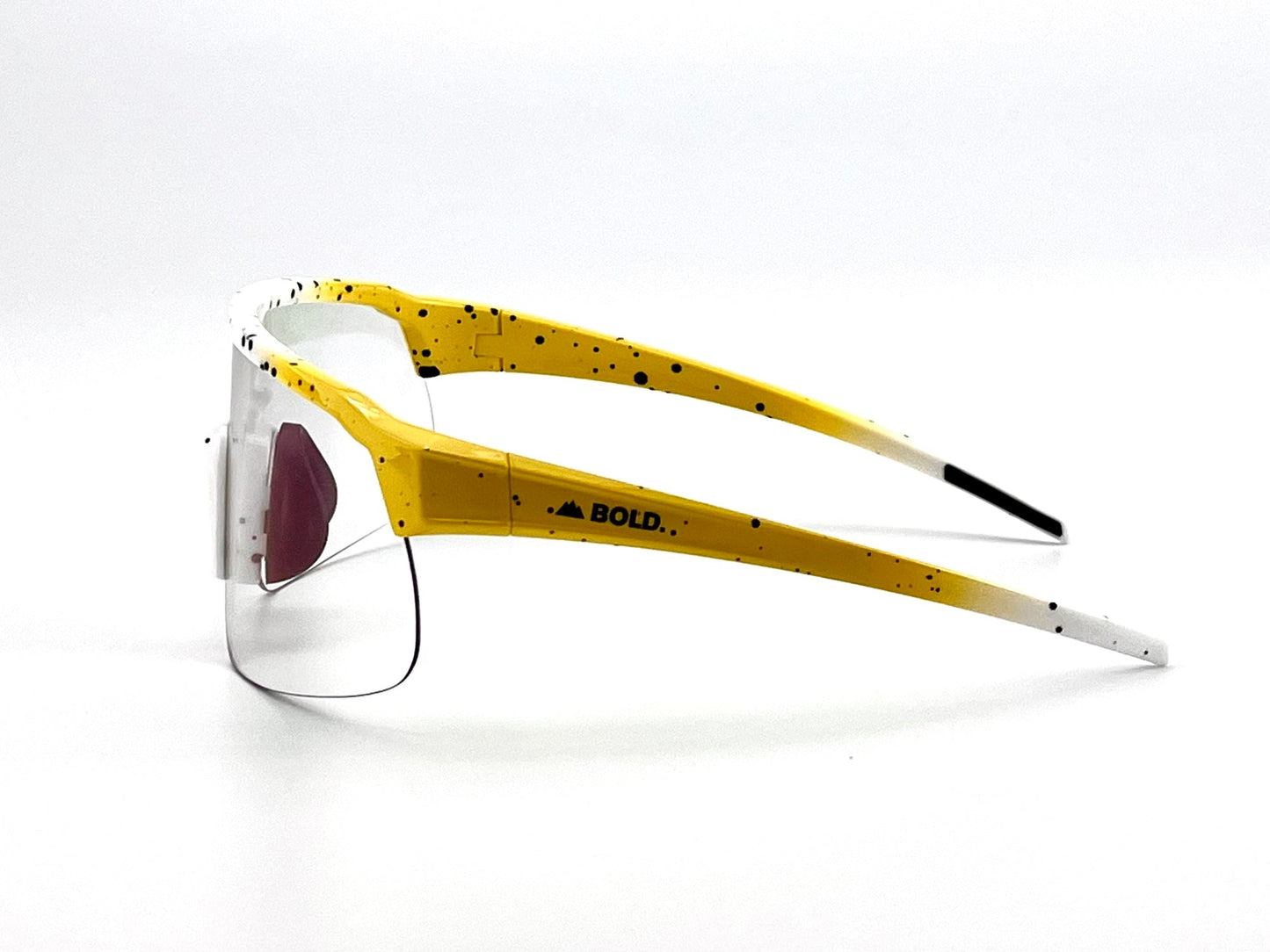 Side view of BOLD Zippy Photochromic Sunglasses by boldouterwear—sporty, lightweight eyewear with a yellow and white speckled frame, rimless clear lenses, “BOLD.” on the arm, black temple tips, and a striking red nose pad.