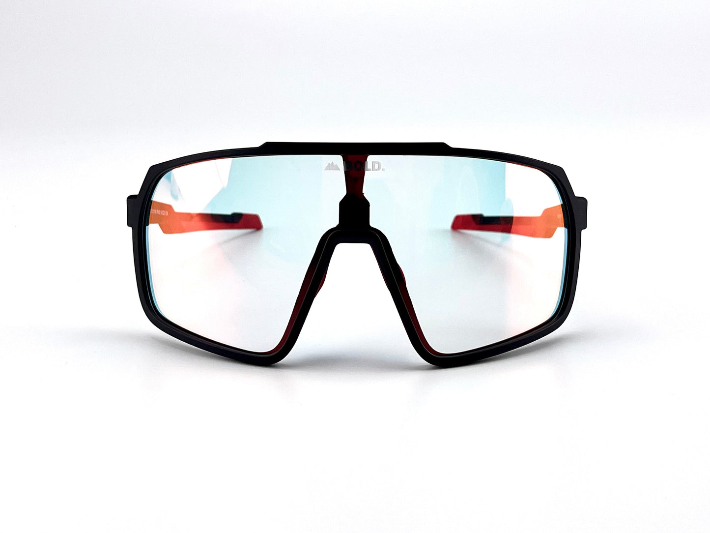 The BOLD Slayers Photochromic Sunglasses by boldouterwear feature a sporty, oversized black frame, large mirrored lenses, and distinctive orange arms. Shown front-facing on a plain white background. Suitable for MTB, ski, and lifestyle wear.