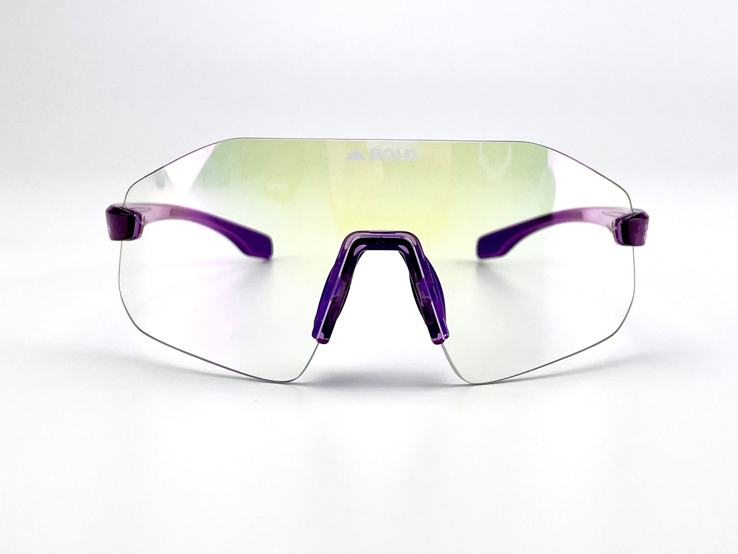 The BOLD Emerald Photochromic Sunglasses by boldouterwear feature a rimless, oversized design with slightly reflective lenses, translucent purple frame and arms, and faint “BOLD” branding at the top center—ideal for MTB, ski & lifestyle use.