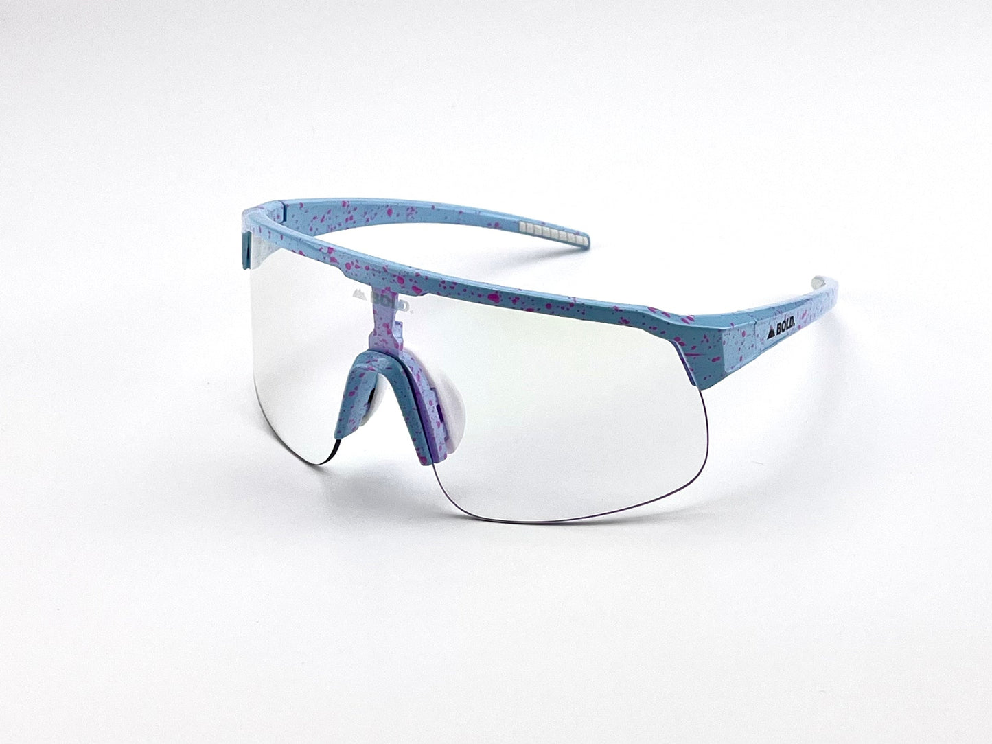 The BOLD Zippy Photochromic Sunglasses by boldouterwear feature a light blue frame with purple speckles, a single clear lens, adjustable nose pad, and straight curved arms with “ALBA” branding, set against a plain white background.