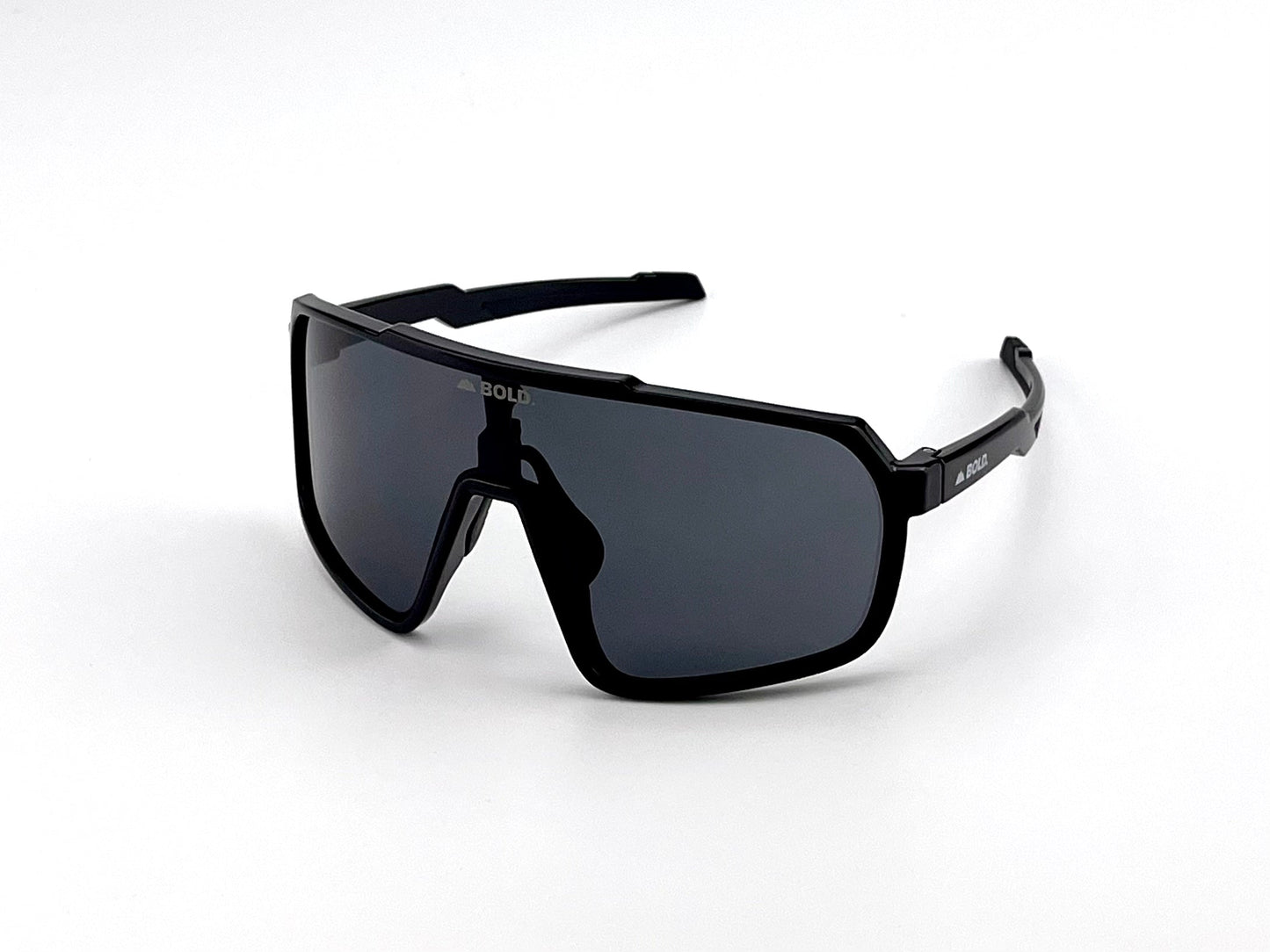 The BOLD Slayers Performance Sunglasses by boldouterwear feature black, angular wraparound frames with dark lenses and "BOLD" printed above the nose bridge. Sporty, geometric design shown on a plain white background. Suitable for MTB, ski & lifestyle use.