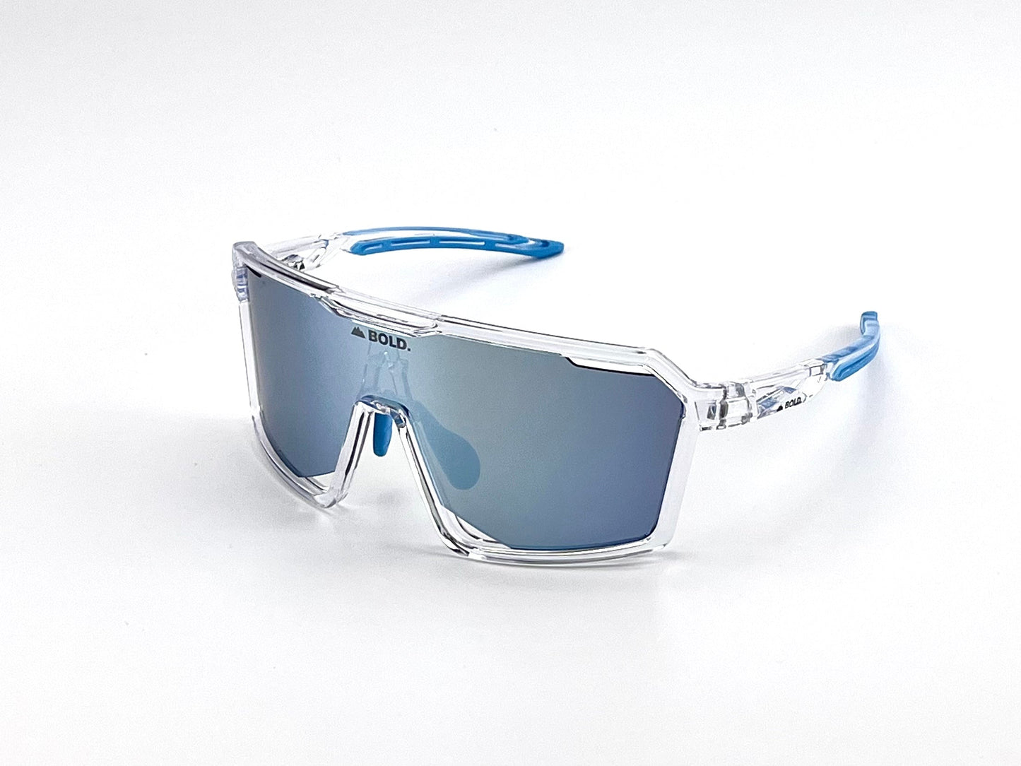 The BOLD Flux Performance Sunglasses by boldouterwear feature a clear plastic frame, blue-tinted mirrored shield lenses, transparent arms with blue tips, and “BOLD.” above the nose bridge. Designed for MTB, ski & lifestyle use with UV protection.