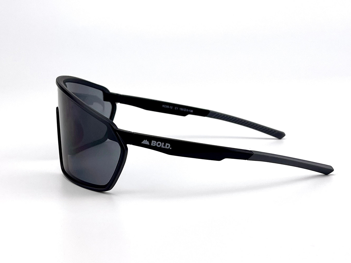 The BOLD NSP Performance Sunglasses by boldouterwear are black, rectangular, dark-tinted sunglasses with sleek frames for smaller faces. "BOLD." and a triangle logo appear on the left arm. Pictured on a seamless white background.
