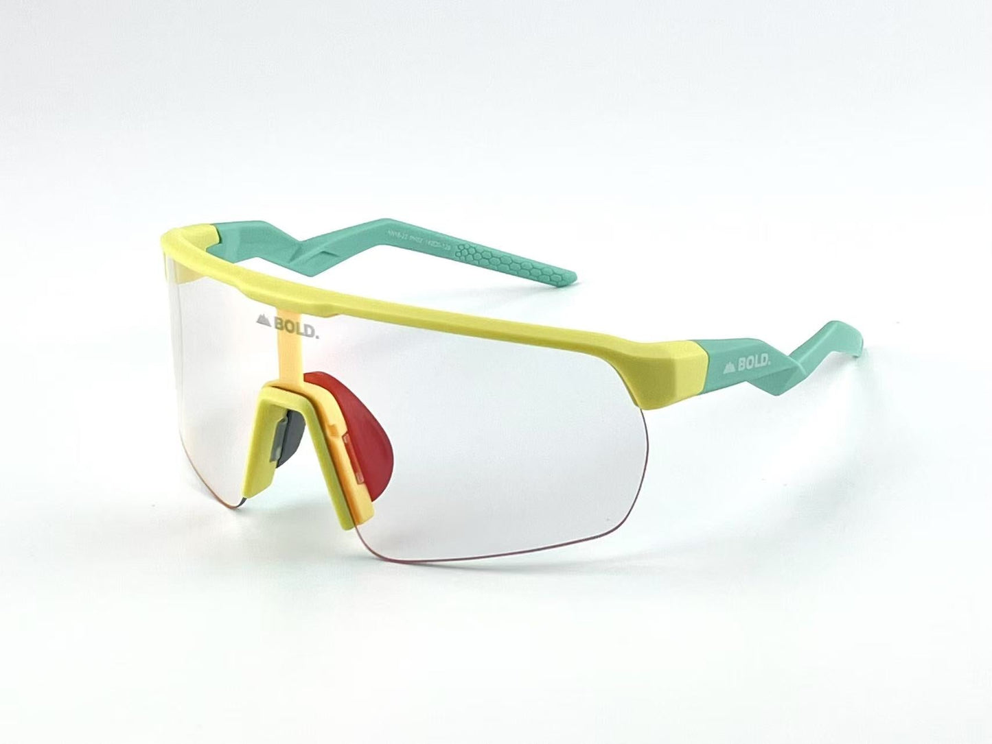 The BOLD Flash Photochromic Sunglasses by boldouterwear feature a single clear lens, yellow frame with red-accented nose bridge, textured teal arms, and “BOLD” branding on the left temple and lens. Shown on a white background.